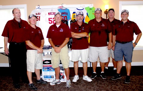 [From left] Athletics Director Kent Keith and Booster Club board members Jason Smothers, Scott Vaughn, Dennis Legrand, Larry Capps, Ed Norton and Brian Taylor stand in front of silent auction items.