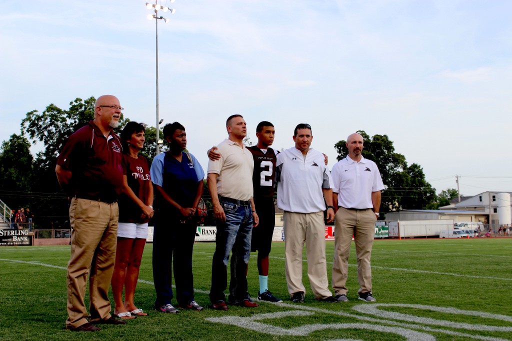 [From left] R-I Superintendent Chris Hon, Sheryl Talkington, Tamara Lewis, Mike Morrow, Caleb Morrow, Jay Dowd and Heath Willis receive a standing ovation during a special recognition prior the opening game against Fox.