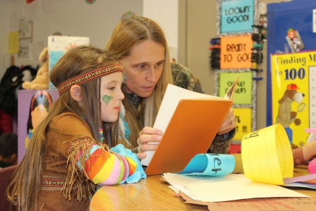 Dressed in camouflage to follow the theme: “hunt for great readers,” Tammi Crosby reads a Thanksgiving book to her first grade daughter Colby, who is dressed as a Native American.