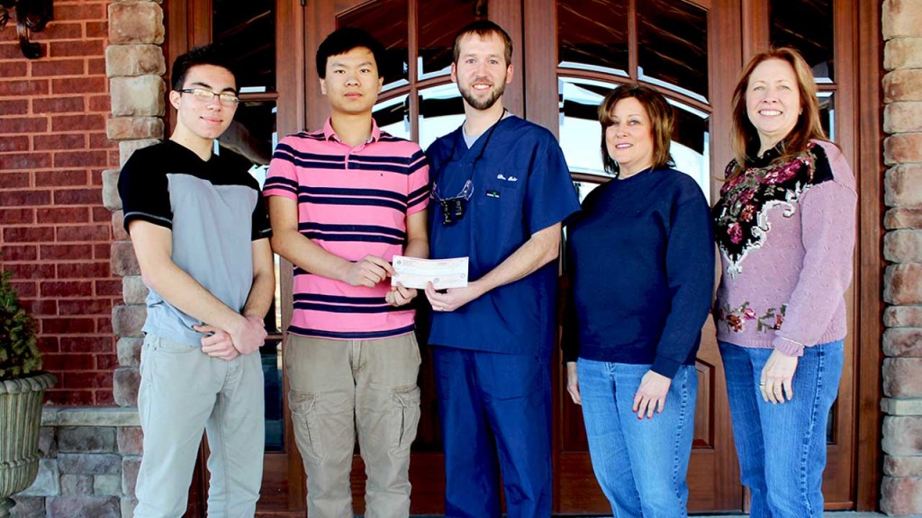 [From left] Robotics Club members Diego Rivetti and Chang Chi accept a check from Dr. Eric Blaich while accompanied by science teachers Patti McCoy and Kathy Miller on Tuesday, Feb. 3, at the Kanell Boulevard facility.