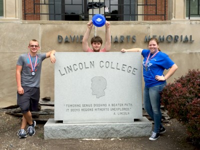 (From left) Jackson Rideout, Christian Cmehil-Warn and Alyssa Cook pose with their spoils outside of Lincoln College following Quizbowl.