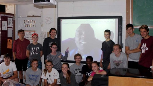 Josphat Boit poses on the projector screen with the Cross Country team.